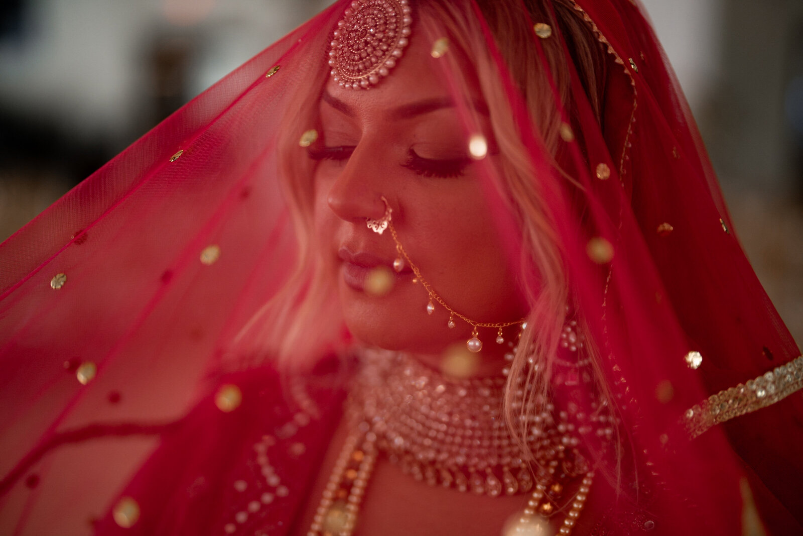 A bride beneath a red and gold veil