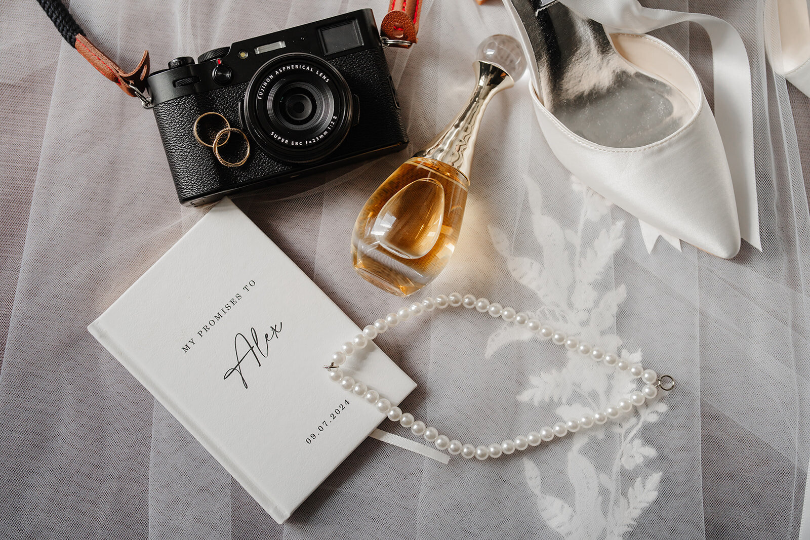 A flatlay of the vow book, rings, perfume and shoes before the ceremony