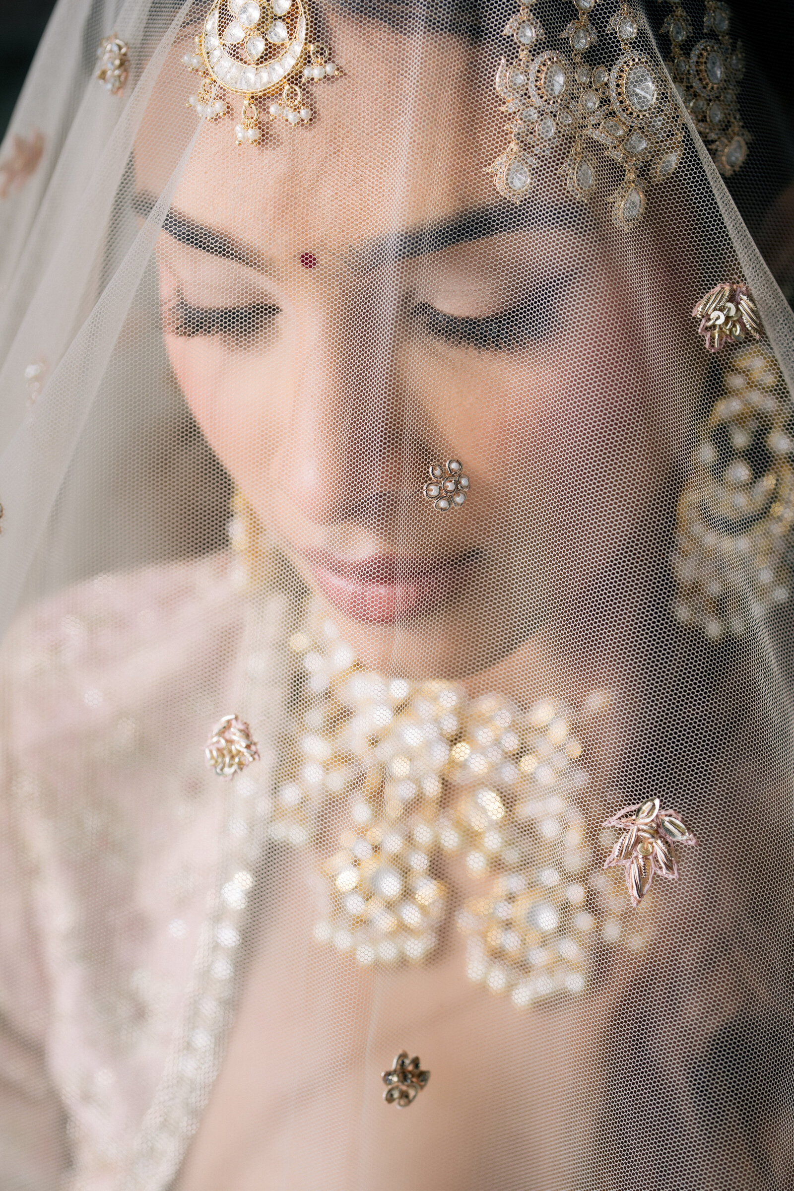 A bride photographed through her veil, jewellery catching the light
