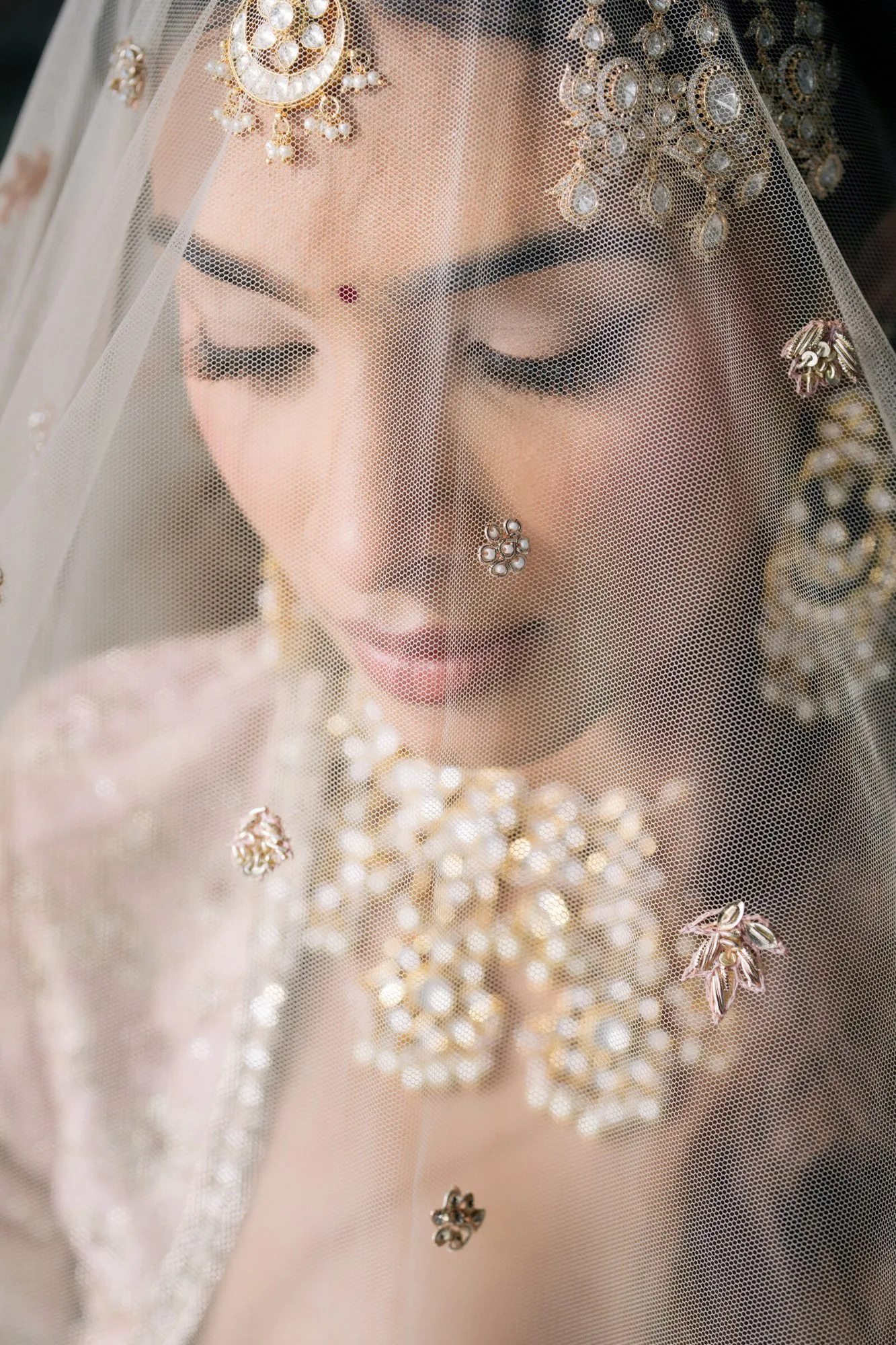 A bride photographed through her veil, jewellery catching the light