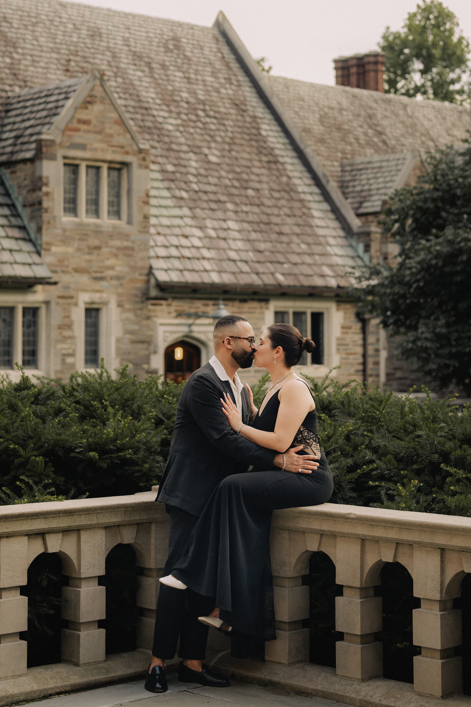Couple kissing on a stone balustrade before a manor house